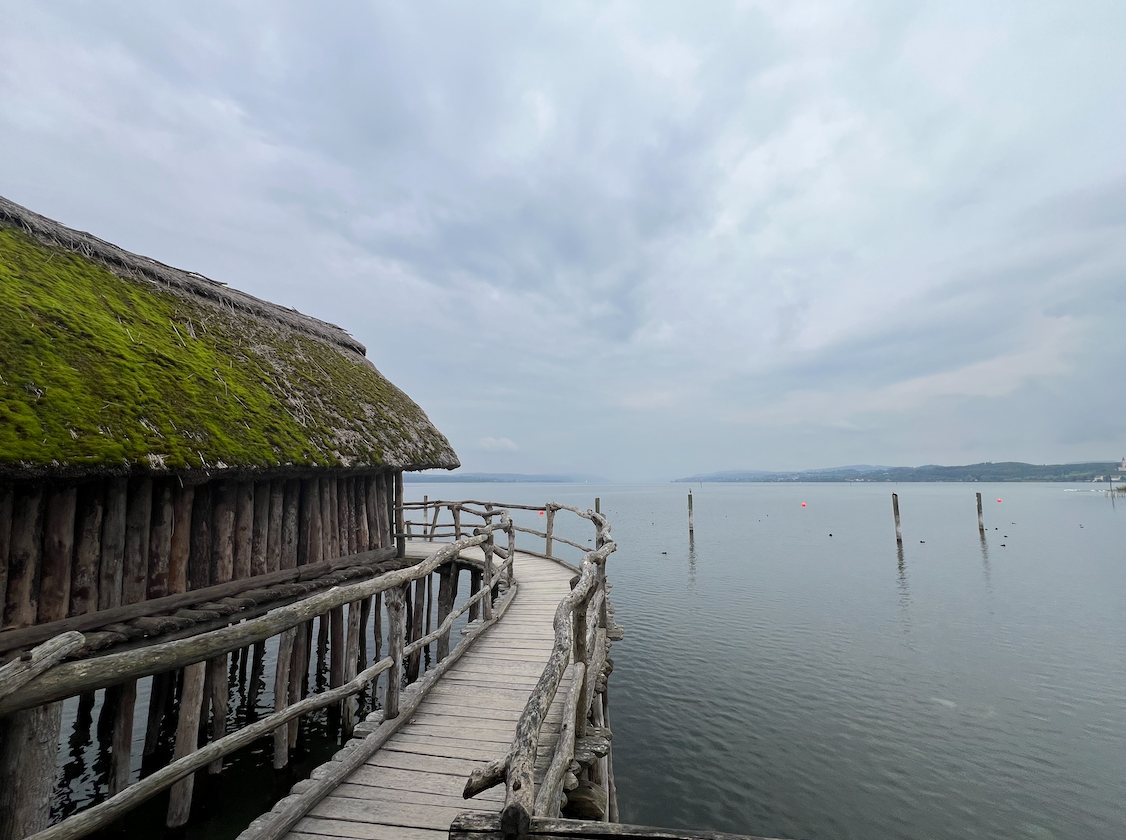 Holzsteg und reetgedecktes Pfahlhaus am Bodensee